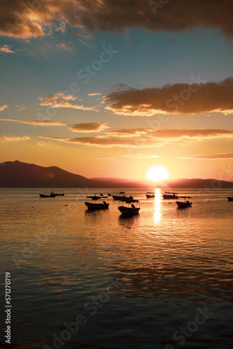 Boats floating on a lake at sunset with clouds in the sky