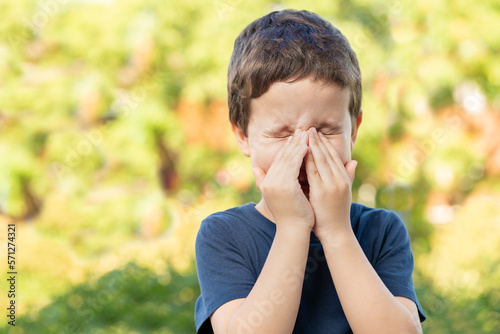 Child with allergy coughing in a green color field in summer © cunaplus