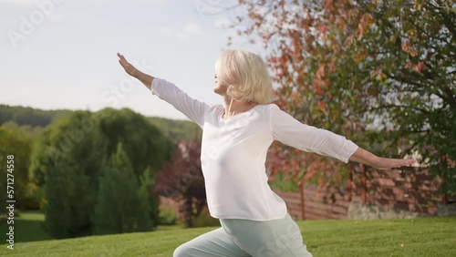 50s grey-haired middle aged mature attractive beautiful old female middle aged senior woman practicing meditation yoga summer nature garden. Calm, good health, happy, relax, healthy lifestyle concept