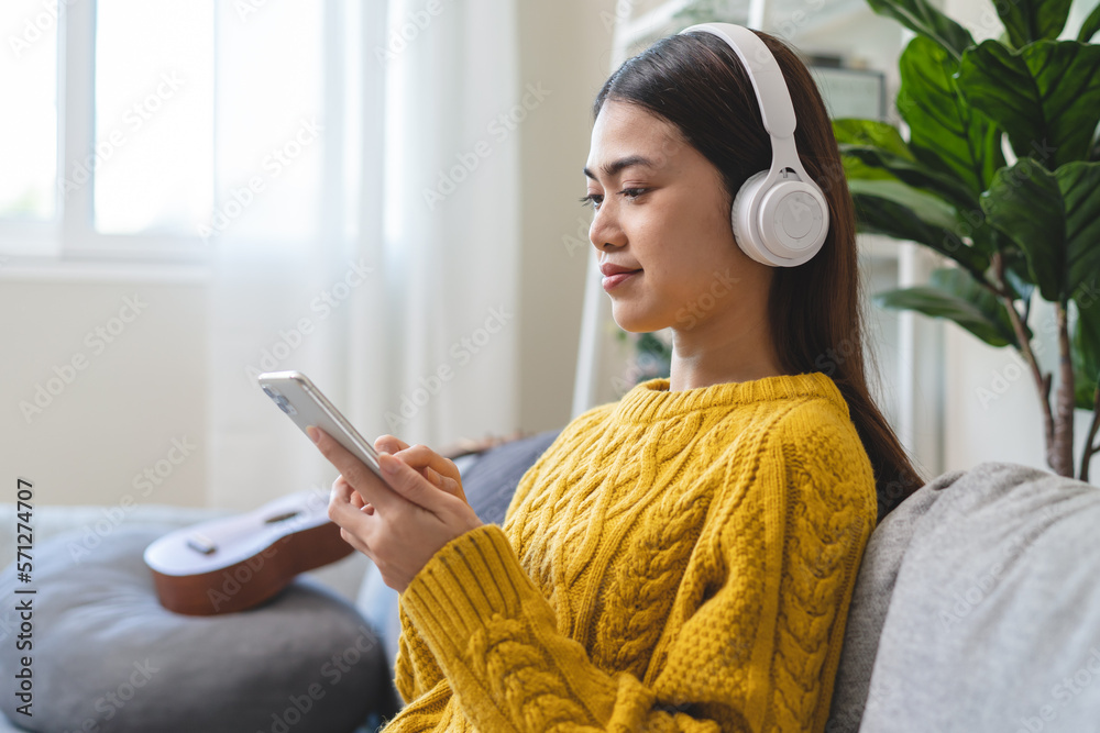 Relax at home on holidays concept, Young Asian female wearing headphone and listening music in the living room. Relax at home on holidays concept, Young Asian female wearing headphone and listening music in the living room.