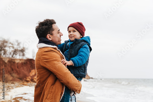 Father holding son in his arms during walk on beach © Drobot Dean