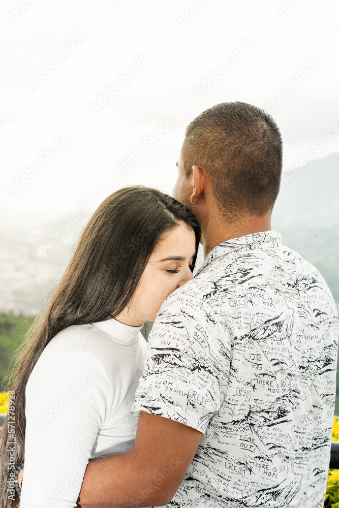 Obraz premium young woman leaning her face on her boyfriend's shoulder, while he looks at the landscape.