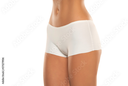 Mid section of woman wearing white briefs, front view on a white background.