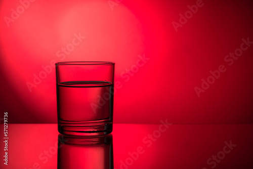 A glass of water. Glass in a backlight. Glass on the red backdrop.