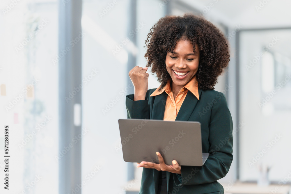 Using laptop computer, Young pretty african american business woman bookkeepers working with balance sheet yearly reports to calculate tax and online consult in modern office.