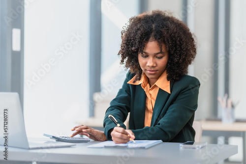 Online consult with laptop, video conference, Young pretty african american business woman bookkeepers working with balance sheet yearly reports to calculate tax and online consult in modern office.