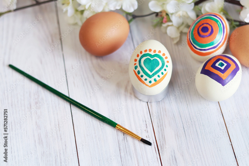 Happy Easter. Coloring eggs at home, Christian holiday, family traditions. Easter eggs on a wooden table on a background with flowers Happy Easter. Coloring eggs at home, Christian holiday, family traditions. Easter eggs on a wooden table on a background with flowers