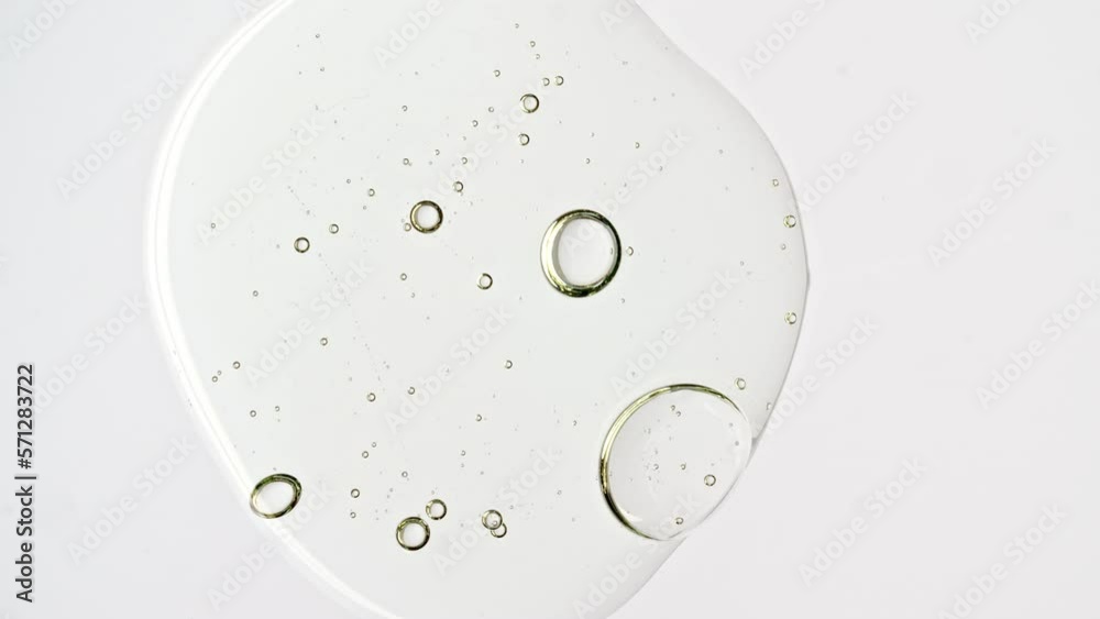 Transparent cosmetic gel fluid with molecule bubbles oil distribution on a white background. Macro Shot of Natural Organic Cosmetics, Medicine. Production Close-up. Slow Motion. High quality 4k. High