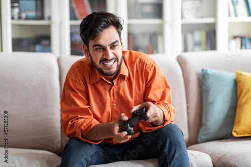 Happy young middle eastern man playing video games at home