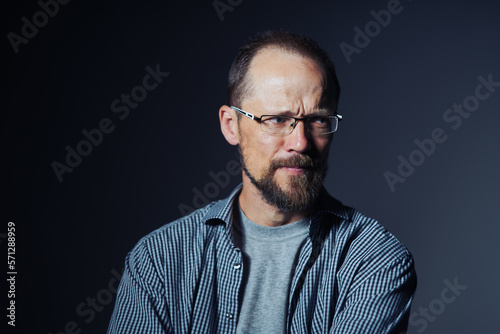 Worried middle age man in shirt frowning eyebrows looking to the side