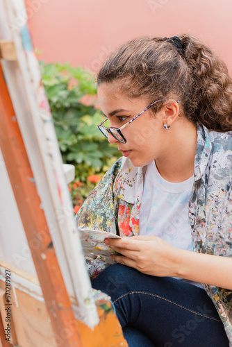 Estudiante adolescente ecuatoriana concentrada en su clase de arte y pintura. Mujer joven latino americana.