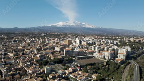 Aerial view of Acireale along the coastline with Etna Volcano during eruption in background, Catania province, Sicily, Italy.