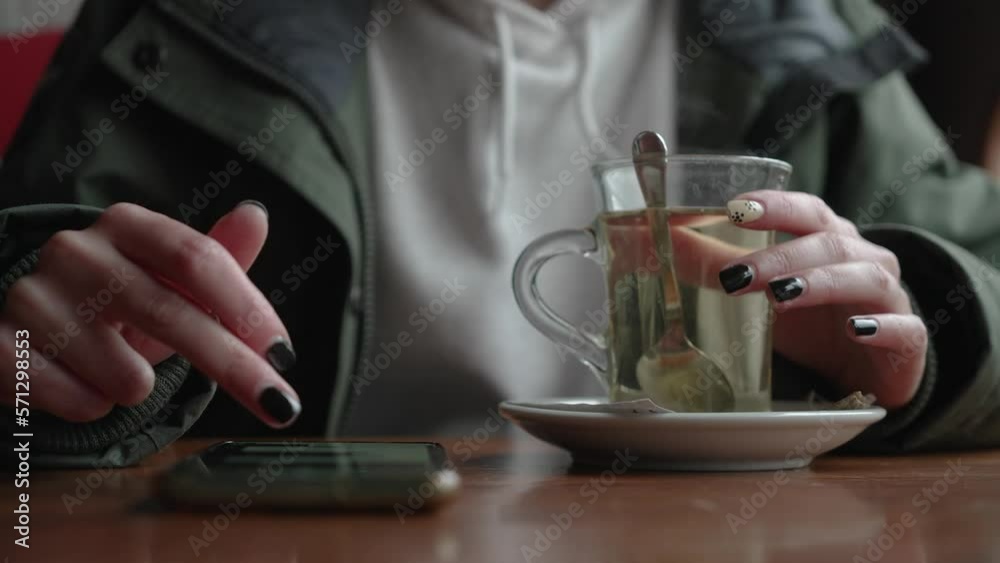 woman drinking tea in winter while using her phone woman drinking tea in winter while using her phone
