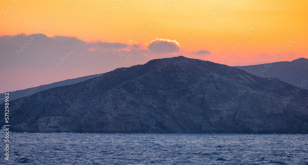 Rocky Island on Mediterranean Sea. Rinia near Mikonos, Greece, Europe. Nature Background. Sunrise Sky