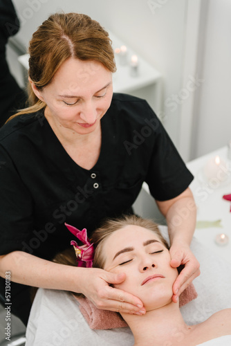 Facial treatment, skincare concept. Relaxing massage. Cosmetologist making rejuvenating face procedures client in spa salon. Aesthetic cosmetology, face care. Girl getting face, head massage treatment