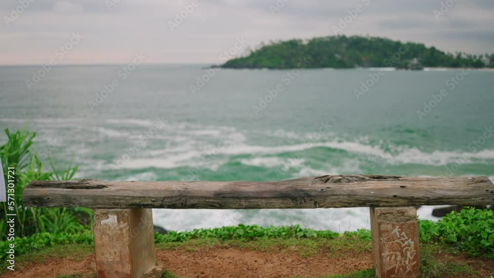 Young blonde woman walks to bench with a spectacular view of ocean, sits down with her her back towards camera slow motion. Pretty girl approaches bench at scenic location and sits enjoying view Young blonde woman walks to bench with a spectacular view of ocean, sits down with her her back towards camera slow motion. Pretty girl approaches bench at scenic location and sits enjoying view