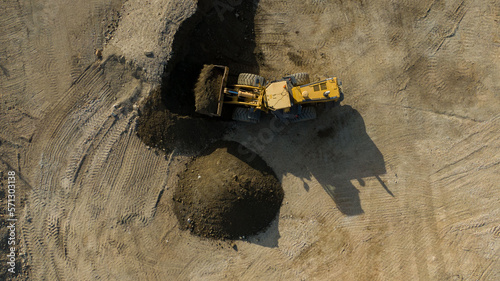 A front end loader machine tipping sand in a quarry