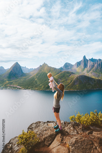 Mother holding up infant baby outdoor family lifestyle traveling in Norway summer vacations woman with child in mountains Senja island aerial view