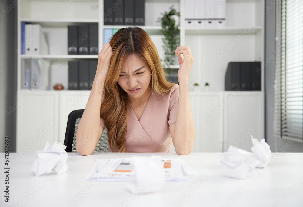 frustrated businesswoman feeling tired from overworked with crumpled paper on the table