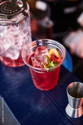 red summer cocktail with lemon and mint top view on blue brane stand, measuring cup, strainer, jiger photo