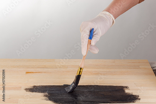 painting wooden background, hand with brush and can of paint