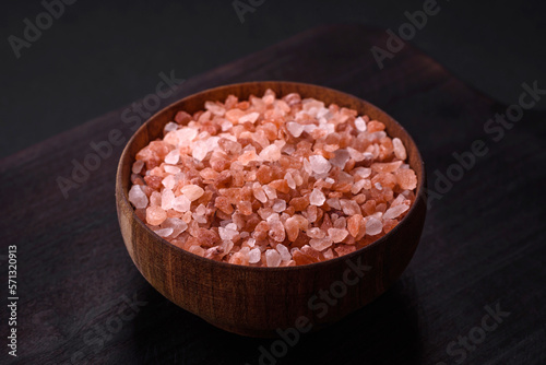 Pink himalayan salt in a wooden bowl on a dark concrete background