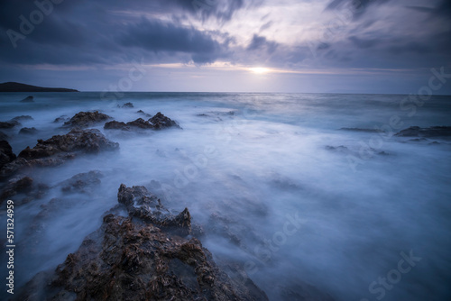 Long exposure shot of rocks on seaside  blurred and foggy sea water and clouds on sky