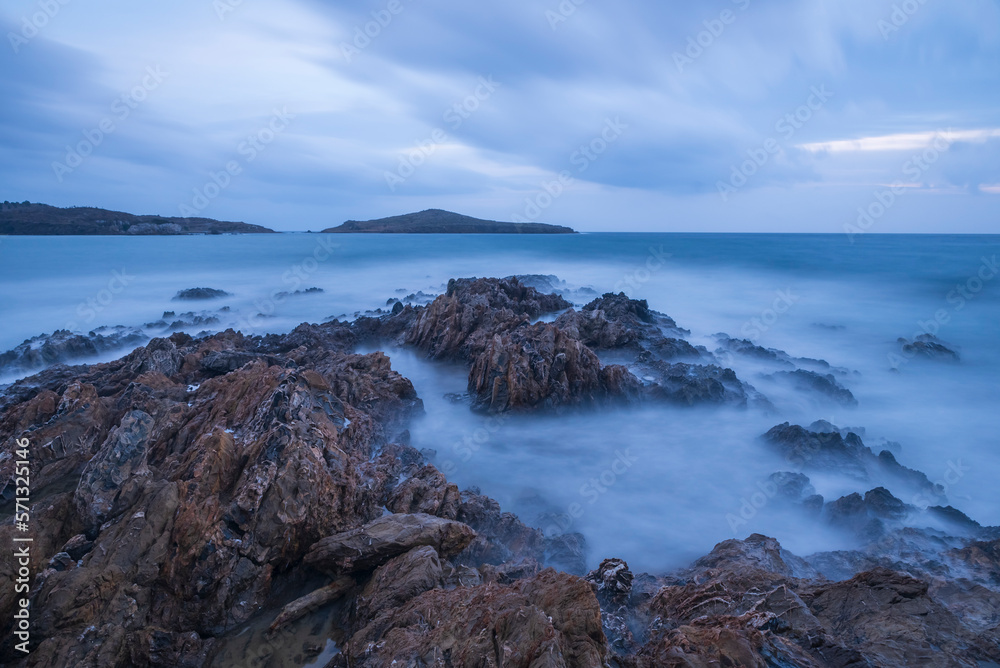 Long exposure shot of rocks on seaside, blurred and foggy sea water and clouds on sky Long exposure shot of rocks on seaside, blurred and foggy sea water and clouds on sky