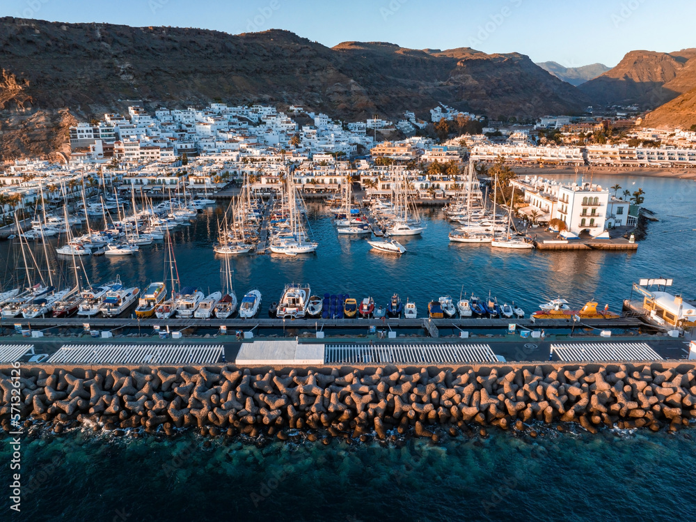 Luxury yachts docked by the golden coast of Spain during magical sunset lights. Luxury holiday concept. Aerial view.