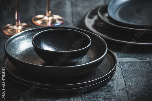 Print op canvas Black stoneware plates and bowls on a rustic black table