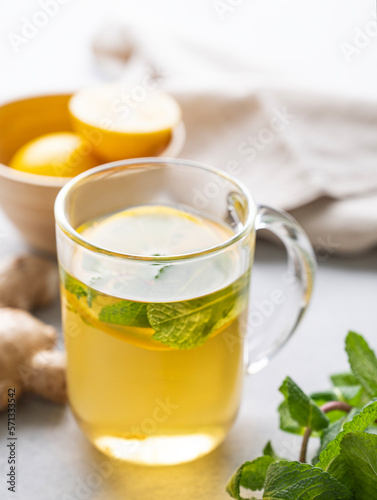 Herbal tea with fresh lemon, mint and ginger on a light background with morning light close up. The concept of a healthy drink.