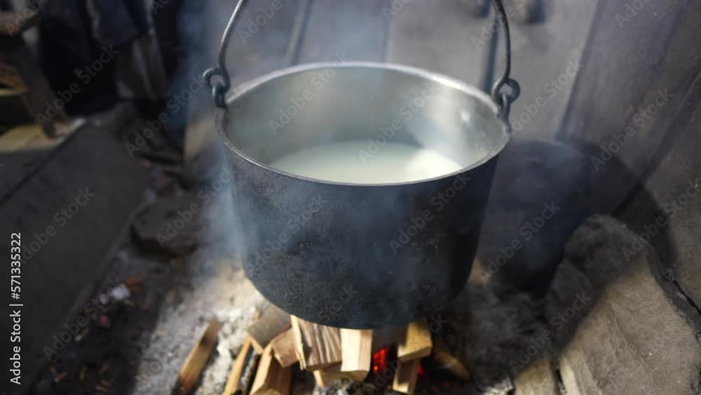 Making organic sheep cheese in wooden mountain Carpathian cheese factory with a boiling smoked cauldron with milk on open fire, Western Ukraine, Europe Making organic sheep cheese in wooden mountain Carpathian cheese factory with a boiling smoked cauldron with milk on open fire, Western Ukraine, Europe