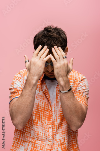 Tablou pe pânză Trendy brunette man in sunglasses covering face isolated on pink.