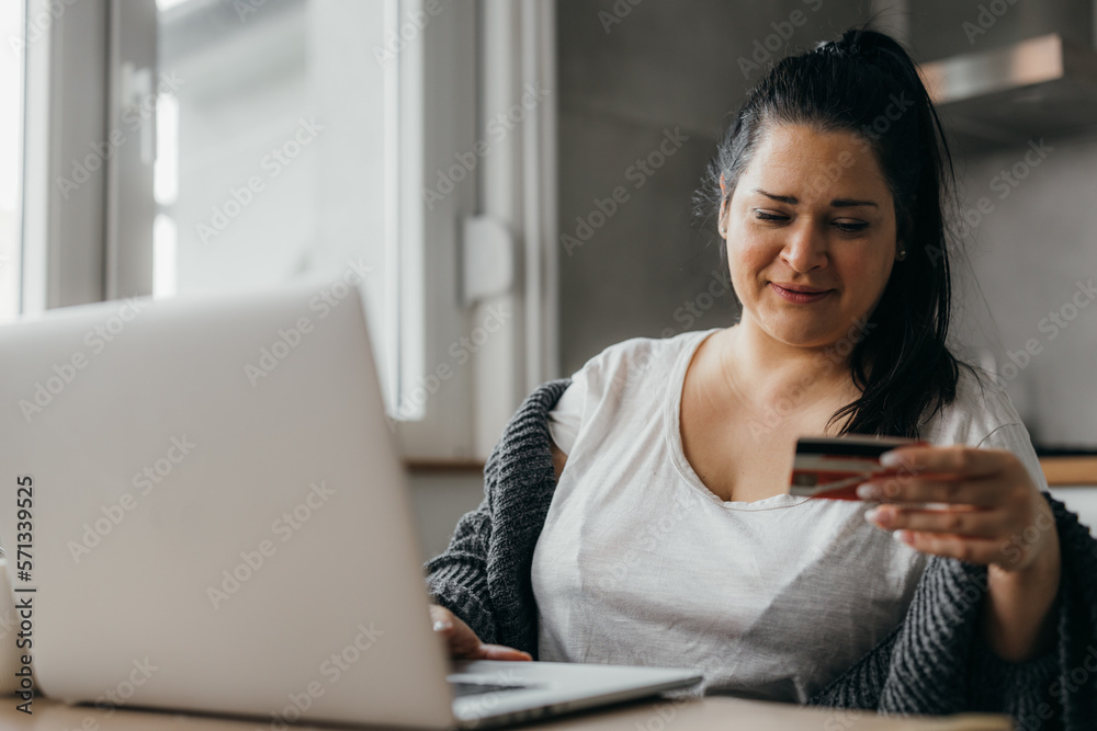 Caucasian woman is looking at her credit card number for online payment