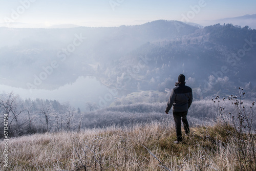 hiking man on the hilltop in the morning, a lake and hills in the background