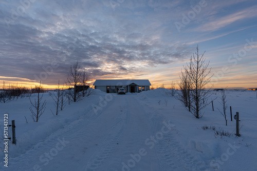 Secluded house in the snow with the ground and the road completely snow covered in residential area of Selfoss in Iceland with the cloudy sky illuminated by the first rays of the sun