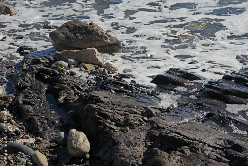 Pacific ocean stone and rock water edge in California after heavy winter storms washed the sand beach away