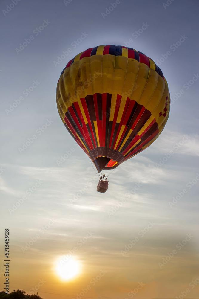 Naklejka premium Multicolored balloon flying in the sky at sunset.