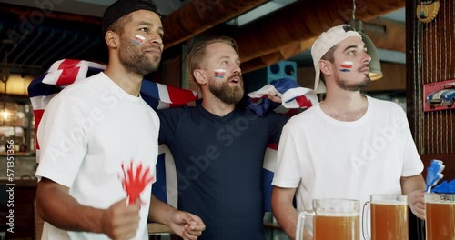 Fans watching football in a bar with friends. football, hockey, basketball, sports games. Men with the flag of the national country of Great Britain drinking beer and watching sport game. photo
