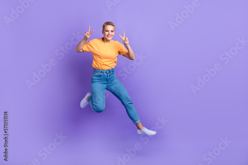 Full body photo of energetic crazy lady jumping show v-sign empty space isolated on violet color background