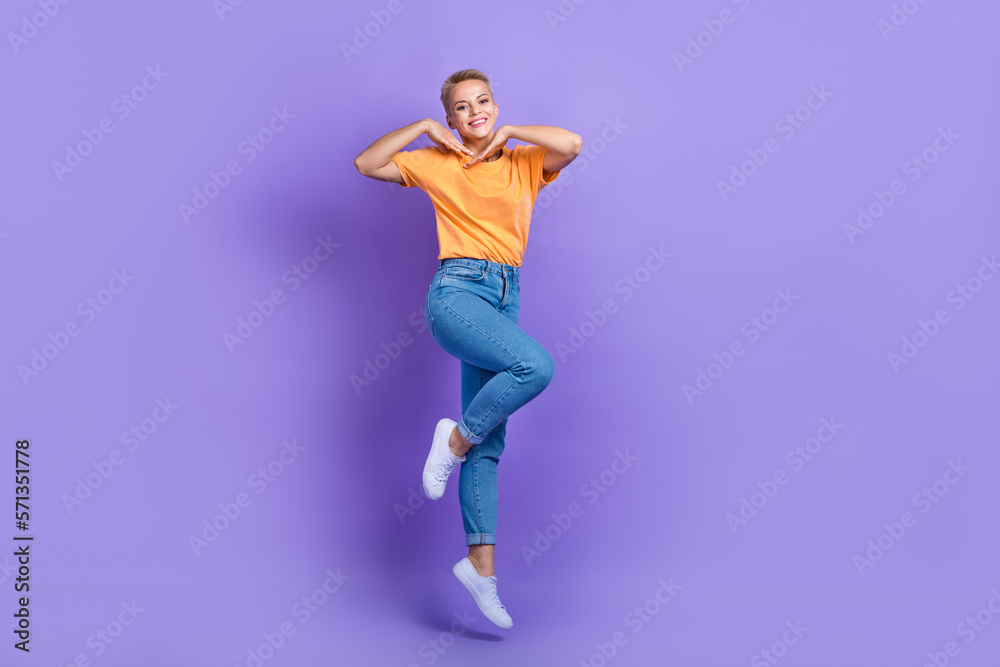 Full size photo of gorgeous optimistic satisfied girl sneakers denim pants hold hands near face isolated on purple color background Full size photo of gorgeous optimistic satisfied girl sneakers denim pants hold hands near face isolated on purple color background