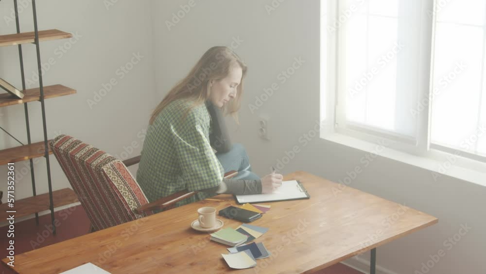 A woman draws on a sheet of paper. Nearby lies a smartphone and a color palette of paints. Home design. Do-it-yourself repair. Budget savings. A woman draws on a sheet of paper. Nearby lies a smartphone and a color palette of paints. Home design. Do-it-yourself repair. Budget savings.
