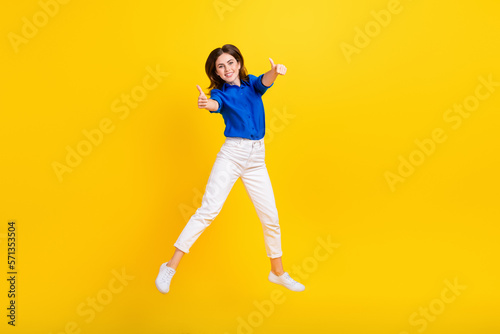 Fototapeta Naklejka Na Ścianę i Meble -  Full length photo of confident sweet lady wear blue shirt rising thumbs up empty space isolated yellow color background