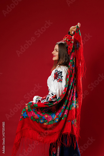 Portrait of ukrainian woman in traditional ethnic clothing and floral red wreath on viva magenta studio background twirls a handkerchief. Ukrainian national embroidered dress call vyshyvanka