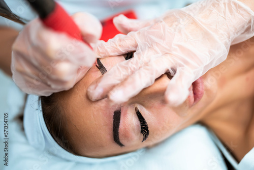 Woman eye with long eyelashes. Beautiful young woman during eyebrows drawing.