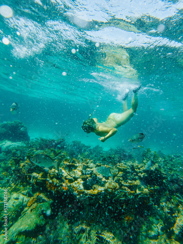young blonde woman diving underwater with goggles