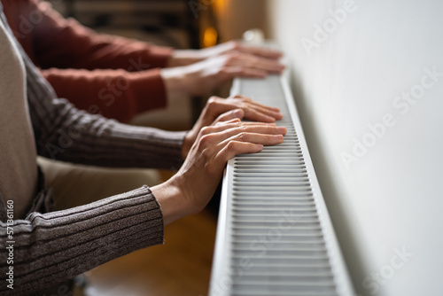 Hands suffering from lack of heat checking temperature electric battery. Palms warming at home radiator. Expensive energy resources  energy crisis in Europe. Saving gas  High price in heating season. 