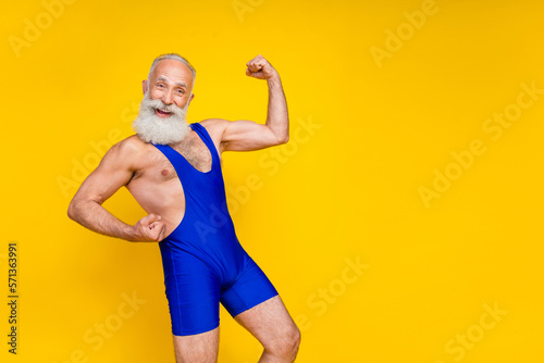 Portrait photo of old age professional bodybuilder pensioner showing demonstrating new blue sportswear big biceps excited isolated on yellow color background