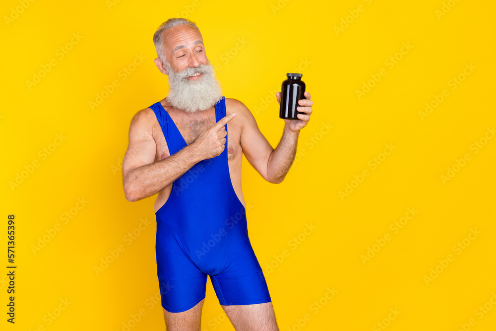 Photo of sporty grandfather indicate finger hands hold empty space supplement bottle isolated on yellow color background