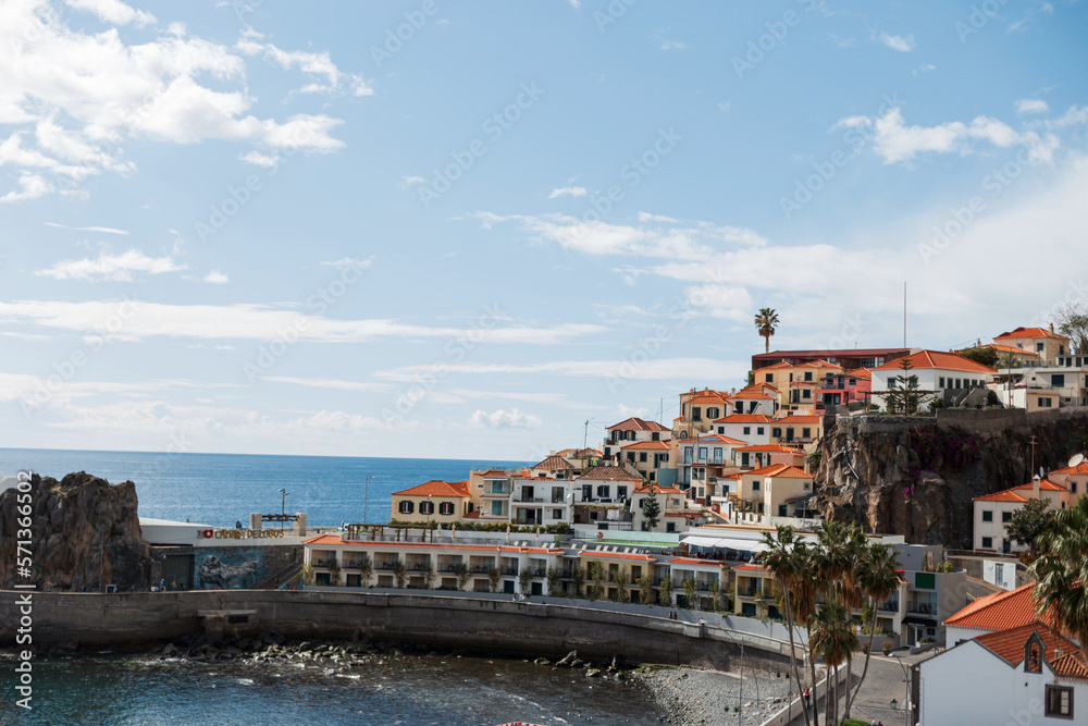 Beautiful fishing town with a house, palm trees and a pier by the ocean on the island of Madeira